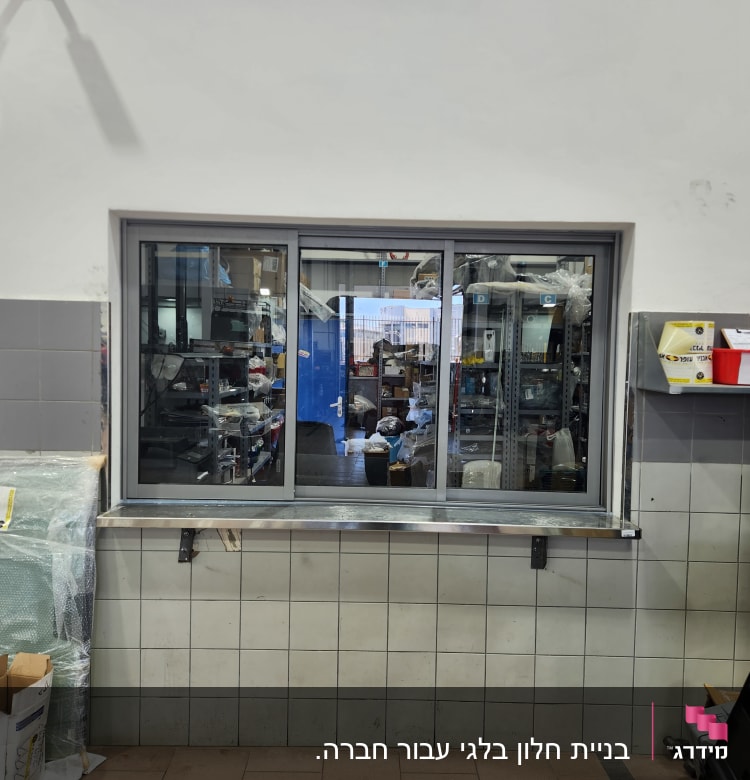 חלון אלומיניום עם מסגרת כסופה במרכז הקיר